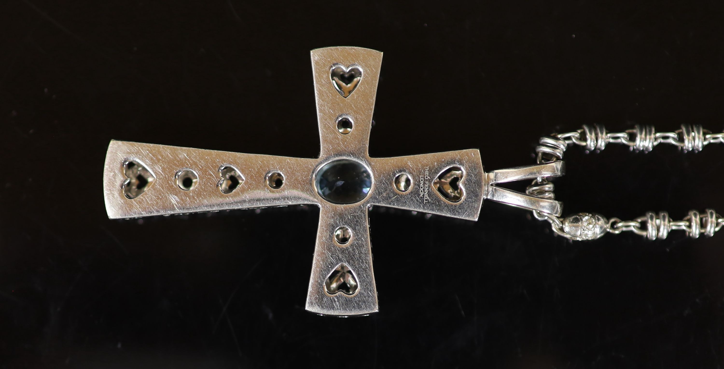 A Theo Fennell white gold, oval cut aquamarine and diamond chip cluster set pierced cross pendant, on a white gold and diamond set chain